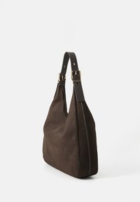 Donkerbruine suède schoudertas met verstelbare leren riem en details met goudkleurige gesp tegen een witte achtergrond.