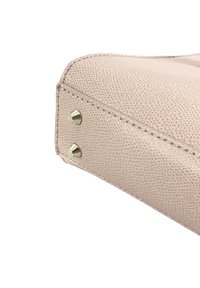 Roze, gestructureerde leren handtas met een hoek die goudkleurige studs, zichtbare stiksels en een licht afgeronde rand heeft.