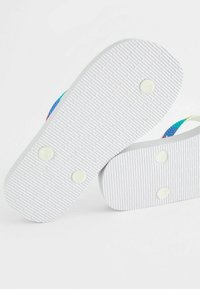 Tongs avec semelles blanches en caoutchouc, texturées pour une meilleure adhérence. Les sangles présentent un motif coloré en bleu, vert et rose. Conception durable et légère.