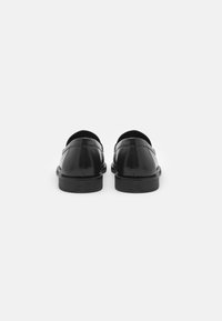 Schwarze Lederschuhe mit glatter Oberfläche, runder Zehenpartie und niedrigem Blockabsatz. Das Design zeichnet sich durch einen Slipper-Stil mit minimaler Naht aus.