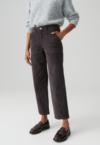 Dark gray corduroy pants with front pockets, a button closure, and a straight-leg design, paired with brown loafers.
