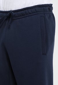 Mörkblå sweatpants i mjukt tyg, med elastisk midja och dragsko, sidofickor och en slät yta.