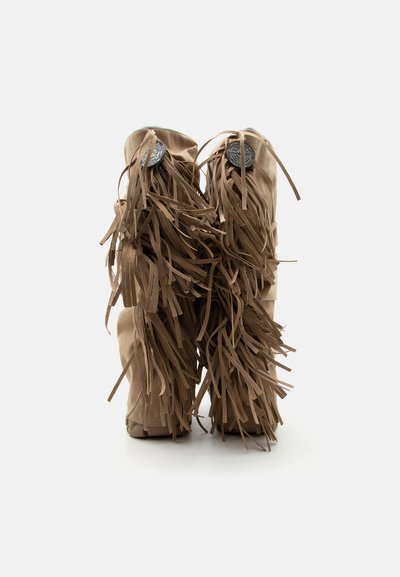 Μπεζ μπότες σουέτ με μακριά κρόσσια και στρογγυλά διακοσμητικά κουμπιά στην πίσω πλευρά, φαίνονται από πίσω με λευκό φόντο.