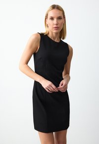 Zwarte mouwloze jurk met een ronde halslijn, op maat gemaakte pasvorm en zichtbare stiklijnen, gemaakt van een gladde stof.