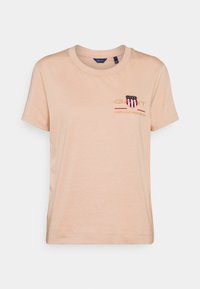 Camiseta de algodón rosa con cuello redondo, mangas cortas y bordado frontal que presenta "GANT", un escudo y el texto "AMERICAN SPORTSWEAR".