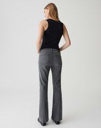 Grijze flare jeans van denim, met een mid-rise taille, achterzakken en een subtiele wassing voor textuur. Gecombineerd met een zwarte tanktop.