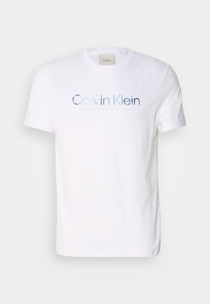 Camiseta de algodón blanca con cuello redondo, mangas cortas y un logo impreso en azul "Calvin Klein" en el pecho.