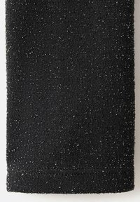 Črna teksturirana tkanina z bleščečo površino, ki ima mehak, puhast občutek ter subtilne bleščice razporejene po materialu.