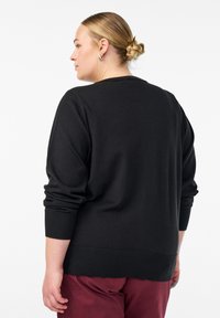 Schwarzer Pullover aus Strickstoff mit langen Ärmeln, gerippten Bündchen und lockerer Passform. Glatte Textur und schlichtes Design.