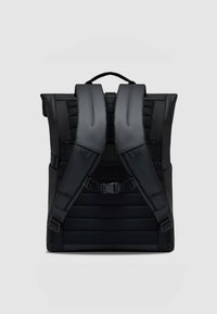 Zaino nero con spallacci imbottiti, pannello posteriore testurizzato e chiusura con fibbia regolabile. Presenta un design elegante e minimalista.