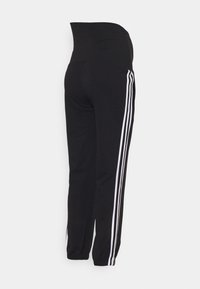 Schwarze Sporthose mit hohem Bund, weißen Seitenstreifen, schmal zulaufendem Bein und elastischen Bündchen an den Knöcheln. Weiche Stoffstruktur.