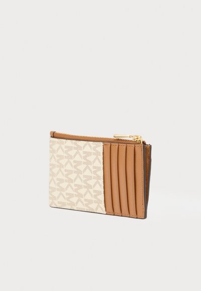Porte-cartes en cuir crème et marron avec un motif graphique. Il est doté d'une fermeture éclair et de plusieurs emplacements pour cartes d'un côté.