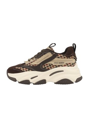 Sneaker chunky con tomaia in suede marrone, tessuto beige e pattern, suola bianca spessa e logo "Steve Madden" sul lato.