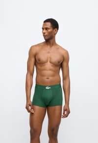 Πράσινα βαμβακερά μποξεράκια με εφαρμοστή γραμμή, με μαλακή μέση και λευκή λεπτομέρεια λογότυπου. Λεία υφή και λιτός σχεδιασμός.