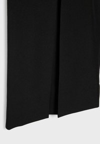 Tissu noir avec une fente verticale centrale à l'ourlet, montrant la texture et des bords parfaitement taillés.