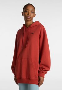 Roter Baumwoll-Hoodie mit einer Vordertasche, Kapuze mit Kordelzug und einem kleinen schwarzen Logo auf der Brust. Weiche Textur und lässige Passform.