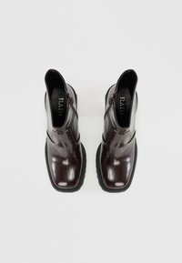 Glänzende dunkelbraune Stiefeletten mit quadratischer Zehenform, seitlichem Reißverschluss und einer strukturierten Gummisohle. Das Innere verfügt über ein schwarzes Logo-Etikett.