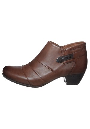 Bottines en cuir marron avec un bout arrondi, des plis diagonaux, une sangle sur le côté avec des accents en métal, et un petit talon empilé.