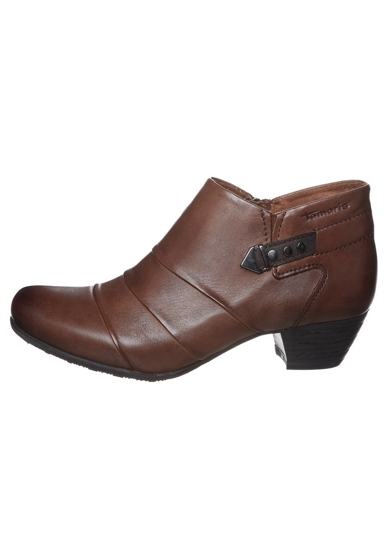 Bottines en cuir marron avec un bout arrondi, des plis diagonaux, une sangle sur le côté avec des accents en métal, et un petit talon empilé.