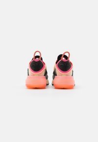 Atletiska skor med en gradienteffekt i svart och beige på ovandelen, rosa detaljer och en räfflad, transparent orange sula. Korta dragflikar vid hälen.