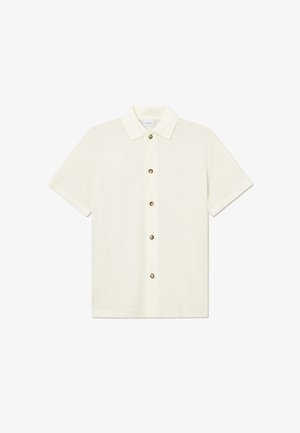 Polo à manches courtes en blanc cassé, avec un tissu texturé, un col classique et cinq boutons marron sur le devant.
