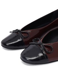 Ballet flats met een bordeaux patent bovenkant, een zwarte patent neuskap, een strikaccent en een gladde, glanzende afwerking.