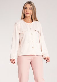 Jasnoróżowa, pleciona kurtka z dwiema kieszeniami na piersi, okrągłym dekoltem, długimi rękawami i złotymi guzikami z przodu, mająca teksturowane wykończenie.