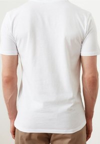 Valkoinen puuvillainen t-paita, jossa on lyhyet hihat, pyöreä kaula-aukko ja sileä pinta. Kuvattu takaa, yksityiskohtina siistit saumat.