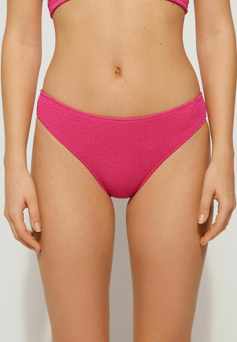 Bas de bikini rose vif avec un tissu texturé, design taille moyenne et bords lisses. Idéal pour les maillots de bain, offrant un ajustement confortable.