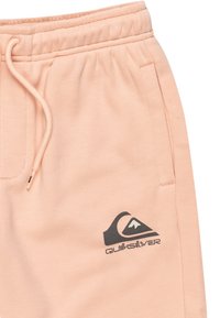 Růžové sportovní šortky z příjemného materiálu s elastickým pasem, šňůrkou na stažení a černým logem Quiksilver vytištěným na levé straně.