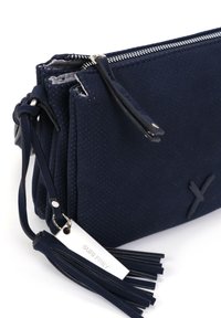 Borsa a tracolla in pelle blu navy con texture perforata, chiusura con zip, dettaglio con nappina e un'etichetta del marchio in argento attaccata.