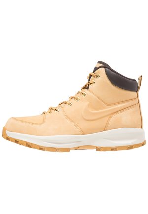 Basket montante en cuir beige avec semelle blanche, œillets dorés, col rembourré noir et languette à tirer au talon.