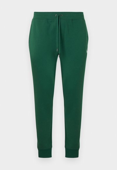 Pantalon de survêtement ajusté vert foncé avec taille à cordon et poignets côtelés, arborant un petit logo blanc brodé sur le côté.