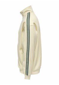 Veste zippée couleur crème avec col montant et trois bandes vert foncé courant le long de la manche, vue de profil.