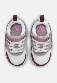 Nike Air tenisky s bílým síťovaným svrškem, světle růžovými koženými akcenty a burgundskými detaily. Mají bílé tkaničky a polstrovaný límec.