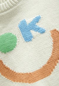 Sweter dziergany w kolorze kremowym z wyrazistym haftem; posiada niebieską literę 'K', zielony okrąg oraz pomarańczowy wzór łuku. Teksturowany materiał.