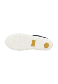 Suela de goma blanca con patrones de agarre texturizados y un logotipo de acento amarillo. Material superior oscuro no visible en esta vista.