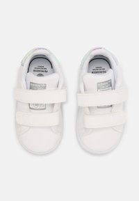 Valkoiset taaperoiden kengät, joissa on kaksi tarranauhaa. Sileä nahkapäällinen, pyöreä kärki ja helmiäiskoristeet kantapäässä. Brändin logo kielen kohdalla.