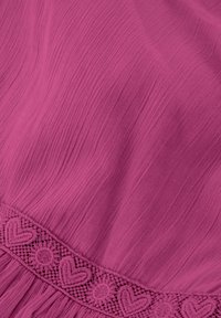 Frambozenroze jurk met een textuurstof, subtiele plooien en een decoratieve kanten rand versierd met hart- en bloemmotieven.