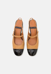 Tan woven slingback shoes with a textured surface, black patent toe cap, and thin ankle strap. Plain brown inner sole.