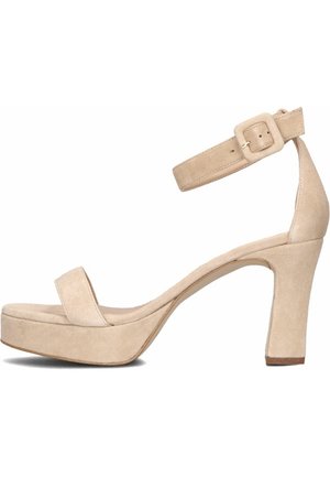 Sandales compensées en daim beige avec une large bride avant, une bride de cheville avec boucle, et un talon haut épais. Texture lisse, design minimaliste.