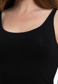 Top senza maniche nero realizzato in tessuto liscio e elasticizzato, con scollatura a barca e spalline sottili.