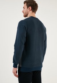 Felpa girocollo navy realizzata in morbido materiale, con pannelli laterali grigi testurizzati e polsini e orlo a costine per un look aderente.