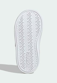 Podešev boty Adidas z gumového materiálu s texturovaným vzorem rybí kosti a vyraženým logem. Převážně bílá s jemným zakřivením na okrajích.