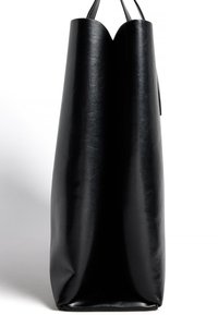 Juodas odinis rankinės krepšys su lygiu paviršiumi, unikalios formos su V formos viršumi ir dviem tvirtais rankenomis nešimui.