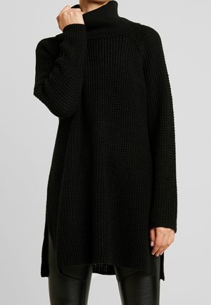 Maglione nero lavorato a maglia con colletto a imbuto, caratterizzato da un motivo a coste testurizzate e spacchi laterali. Maniche lunghe e ampie, progettate per il comfort.