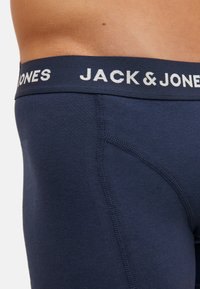 Boxers bleu marine en tissu doux, avec une ceinture logo blanche et des détails de couture, offrant un ajustement confortable et une texture lisse.