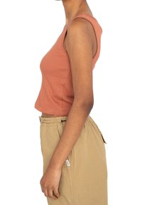 Débardeur côtelé couleur rouille avec une coupe courte. Le tissu semble doux, doté d'une silhouette ajustée et de larges bretelles.