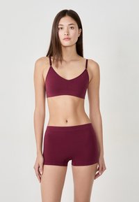 Ensemble bralette et boyshort bordeaux en tissu doux. Le bralette dispose de bretelles ajustables, tandis que le short présente une taille sans couture.