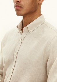 Lichtbeige linnen shirt met een button-down kraag, voorzien van een textielstructuur en zichtbare knopen op de voorste sluiting.